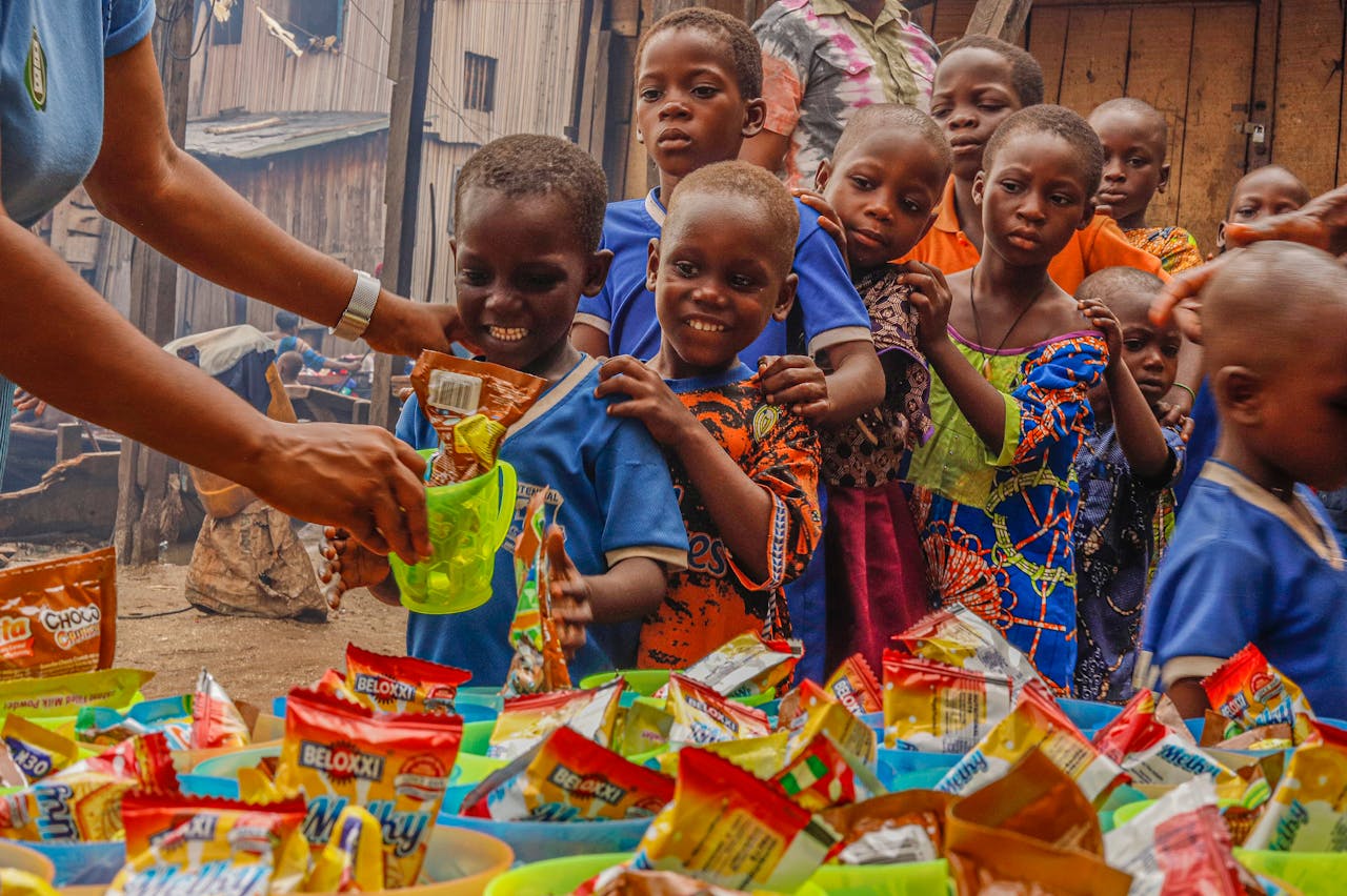 services-01 Joyful children receiving food supplies from a volunteer in an outdoor setting.